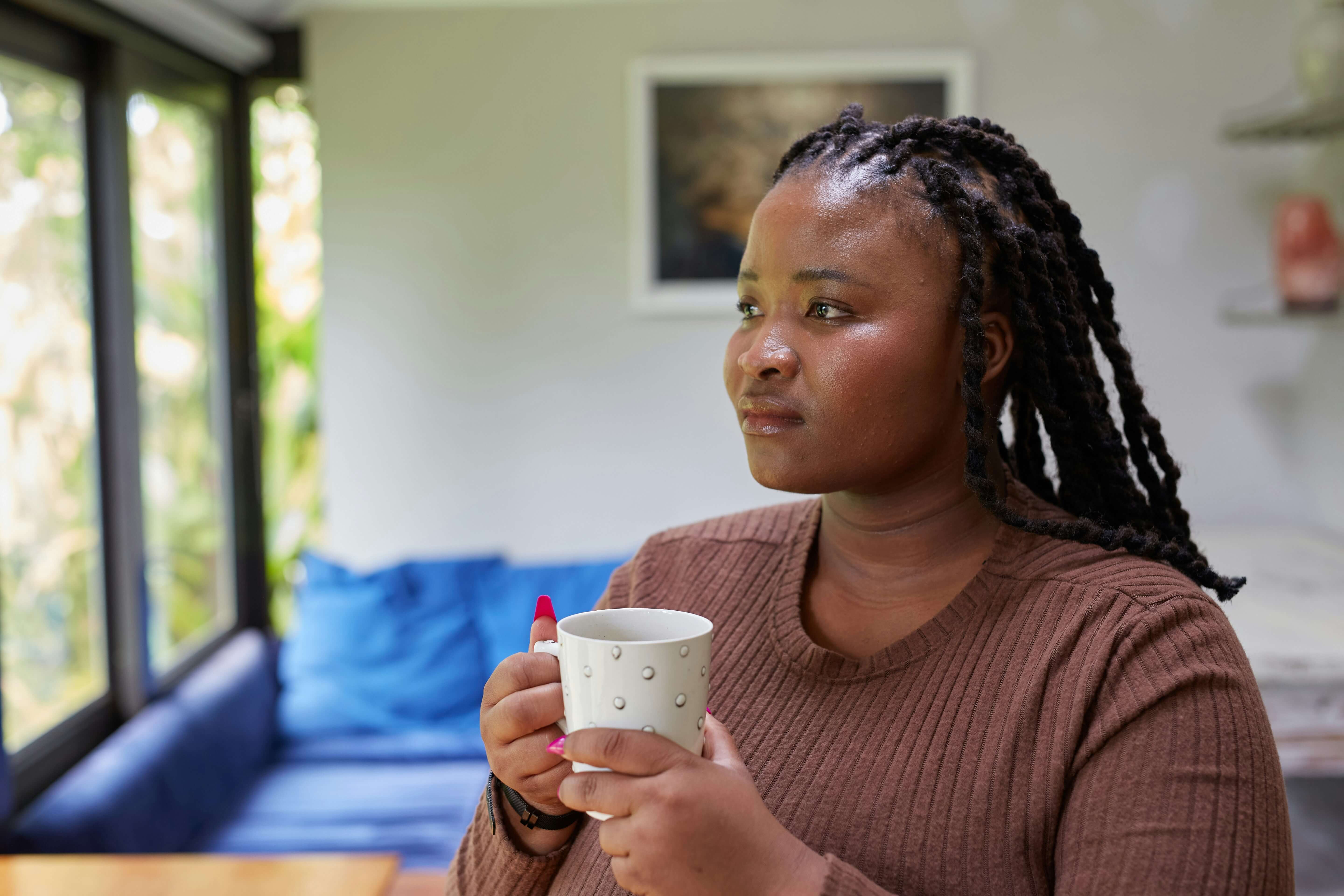 A woman looking thoughtful holding a cup of tea